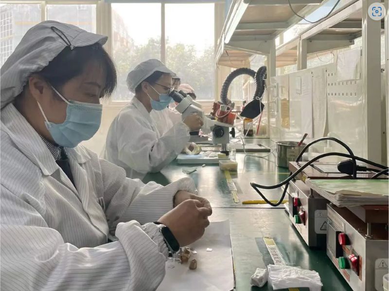 Cleanroom assembly operators building ferrite microstrip/drop-in modules under microscopes