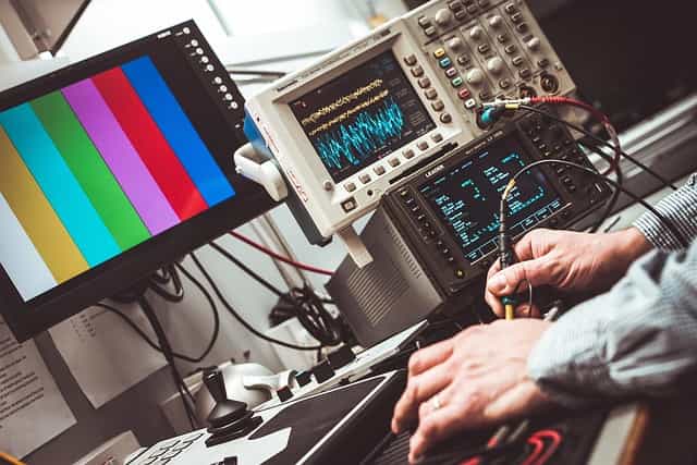 Engineer tuning RF test equipment with oscilloscopes in a microwave lab
